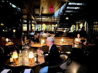 Salle du restaurant Sartiano’s à l’ambiance feutrée, éclairée par des lampes tamisées, clients attablés
