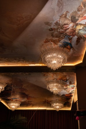 Plafond orné de fresques et lustres en cristal reflétant une lumière dorée