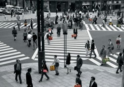 Scène urbaine au Japon en noir et blanc avec des passants tenant des sacs Louis Vuitton colorés.