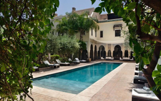 Piscine centrale bordée de transats et d’oliviers à la Villa des Orangers, Marrakech