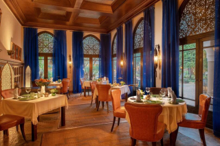 Salle de restaurant élégante avec grandes fenêtres et rideaux bleus à la Villa des Orangers