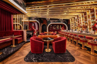 Un bar feutré à l'Americano, ambiance tamisée et canapés profonds en velours rouge, discret et élégant