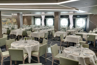 Salle de restaurant élégante avec grandes tables et hublots à bord du MSC Seaside