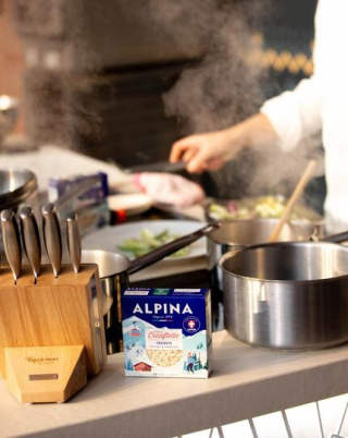 Un chef prépare un plat avec les crozets Alpina sur un plan de travail.