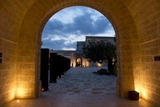 L’entrée principale du Relais Histó, majestueuse sous la voûte éclairée au crépuscule.