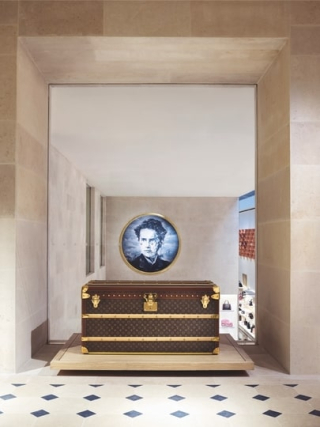 Installation présentant le portrait de Louis Vuitton et une malle historique dans un espace patrimonial de la Maison.