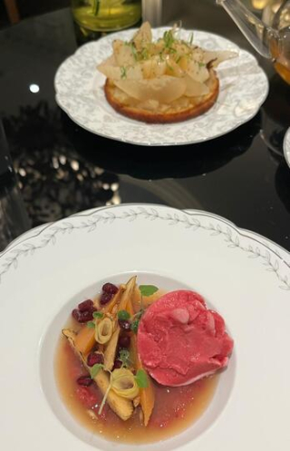 Assiette composée d’un sorbet aux épices avec garnitures végétales et une tarte aux poires en arrière-plan