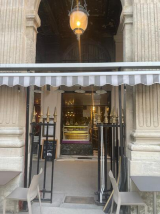 Façade de la boutique Muscade, avec ses colonnes en pierre, son luminaire suspendu et son comptoir intérieur.