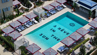 Piscine de l'hôtel AREV bordée de parasols rayés bleu et blanc.