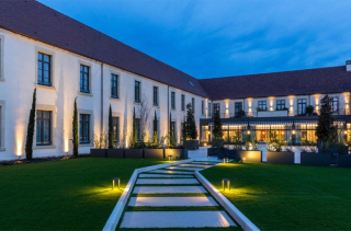 La façade éclairée des 7 Fontaines à Tournus au crépuscule, son jardin et son allée de dalles lumineuses.