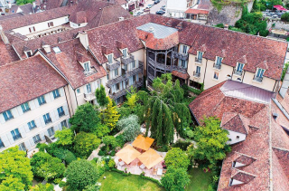Vue aérienne du Relais Bernard Loiseau à Saulieu, ses toits de tuiles et son jardin intérieur aux parasols orangés.