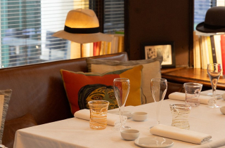 Une table dressée chez Stern Ristorante à Paris, près d'une lampe coiffée d'un chapeau.